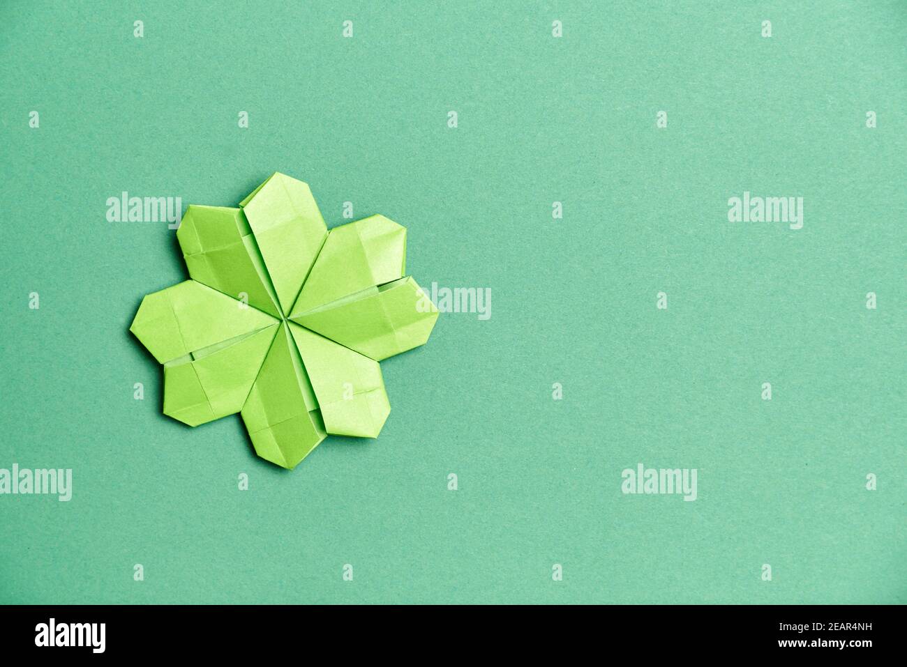 shamrock à quatre feuilles d'origami, en papier vert clair, sur fond vert. Concepts de chance et de la Saint-Patrick. Image avec espace de copie. Banque D'Images