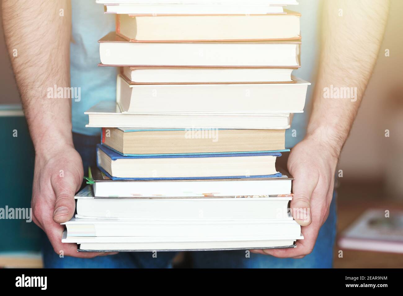 Un homme tient une pile de livres dans ses mains. Une photo sans visage. Un amoureux de la lecture. Banque D'Images