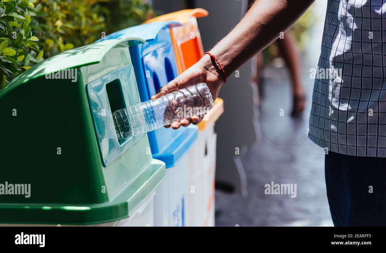 main noire jetant une bouteille d'eau en plastique vide dans le recyclage des déchets Banque D'Images