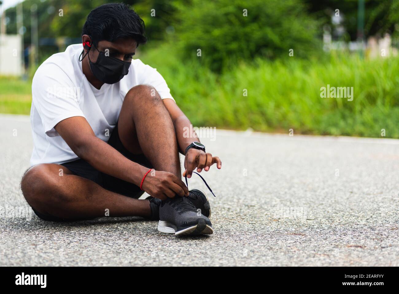 coureur noir homme porter masque de protection il a cordonnet essayer chaussures de course à pied Banque D'Images