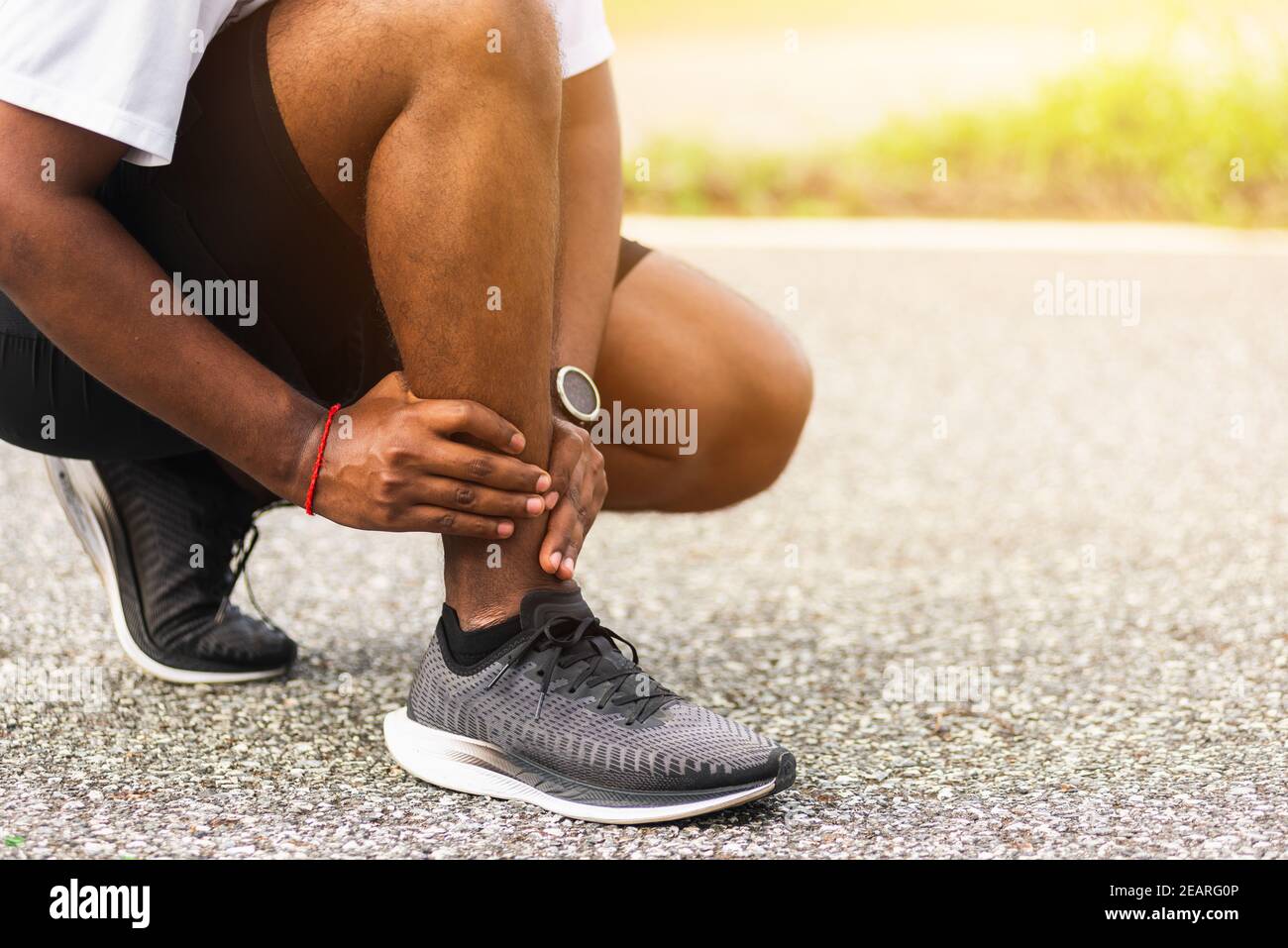 sport coureur homme utiliser les mains joint tenir la douleur de jambe parce que de la cheville tordue brisée pendant la course Banque D'Images