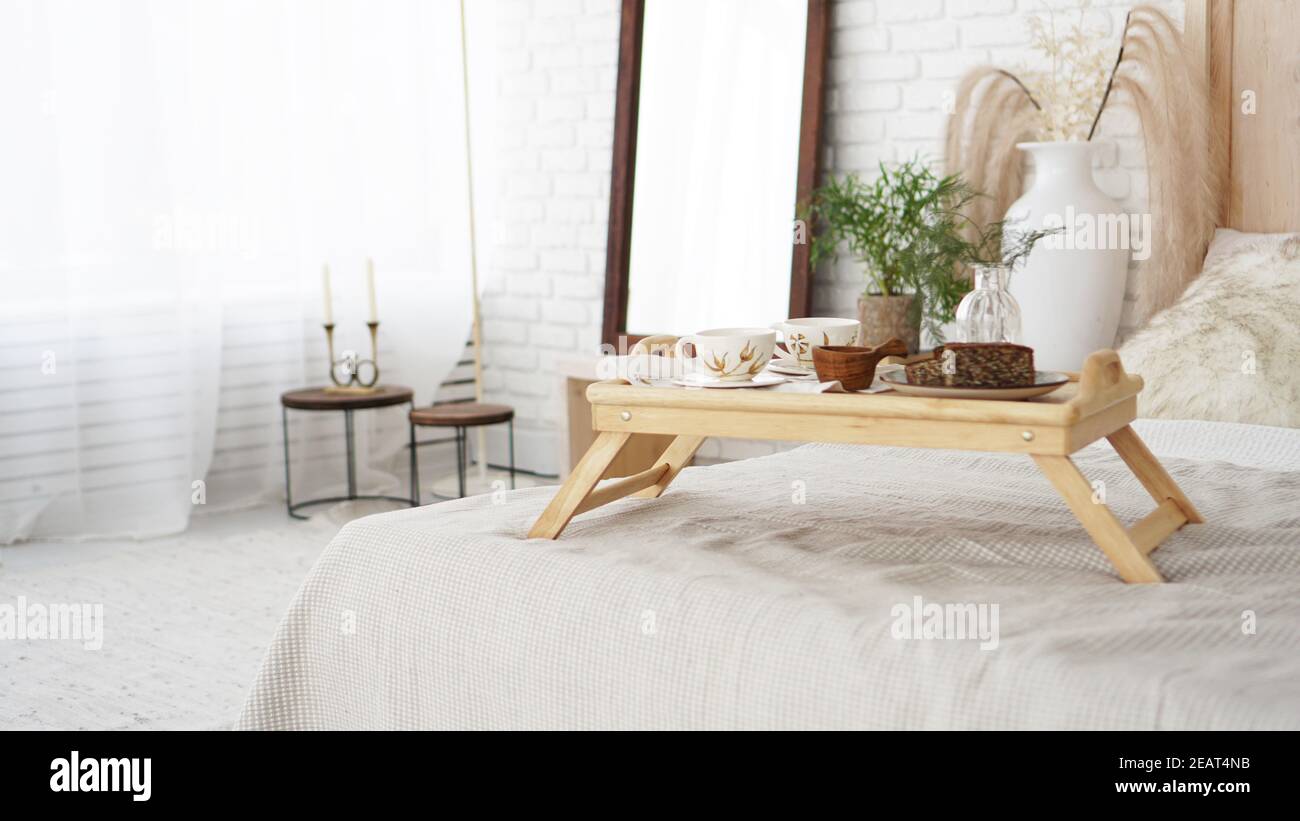 Petit déjeuner servi en gros plan dans la chambre. Tasses sur un plateau avec vase sur le lit. Mise au point sélective. Style scandinave. Banque D'Images