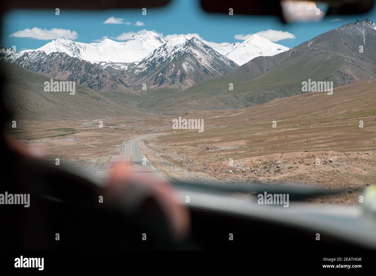 Conduite de la route de la soie, à travers la vallée vide avec des sommets de montagne en arrière-plan Banque D'Images