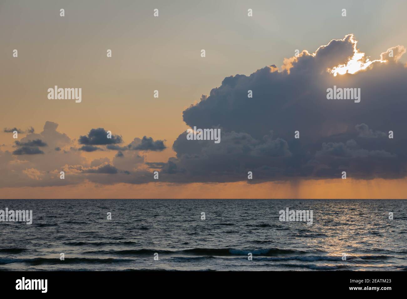Soleil brillant à travers des cumulus sombres nuages ciel au-dessus de la surface de la mer en soirée. Paysage nuageux et moelleux avec lumière du soleil sur la mer bleu foncé Banque D'Images