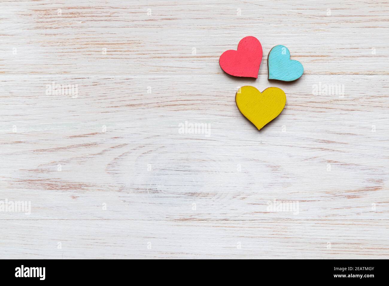Trois coeurs en bois colorés sur fond de bois vintage. Vue de dessus. Pose à plat. Copier l'espace. Symbole de l'amour. Composition de la Saint-Valentin Banque D'Images