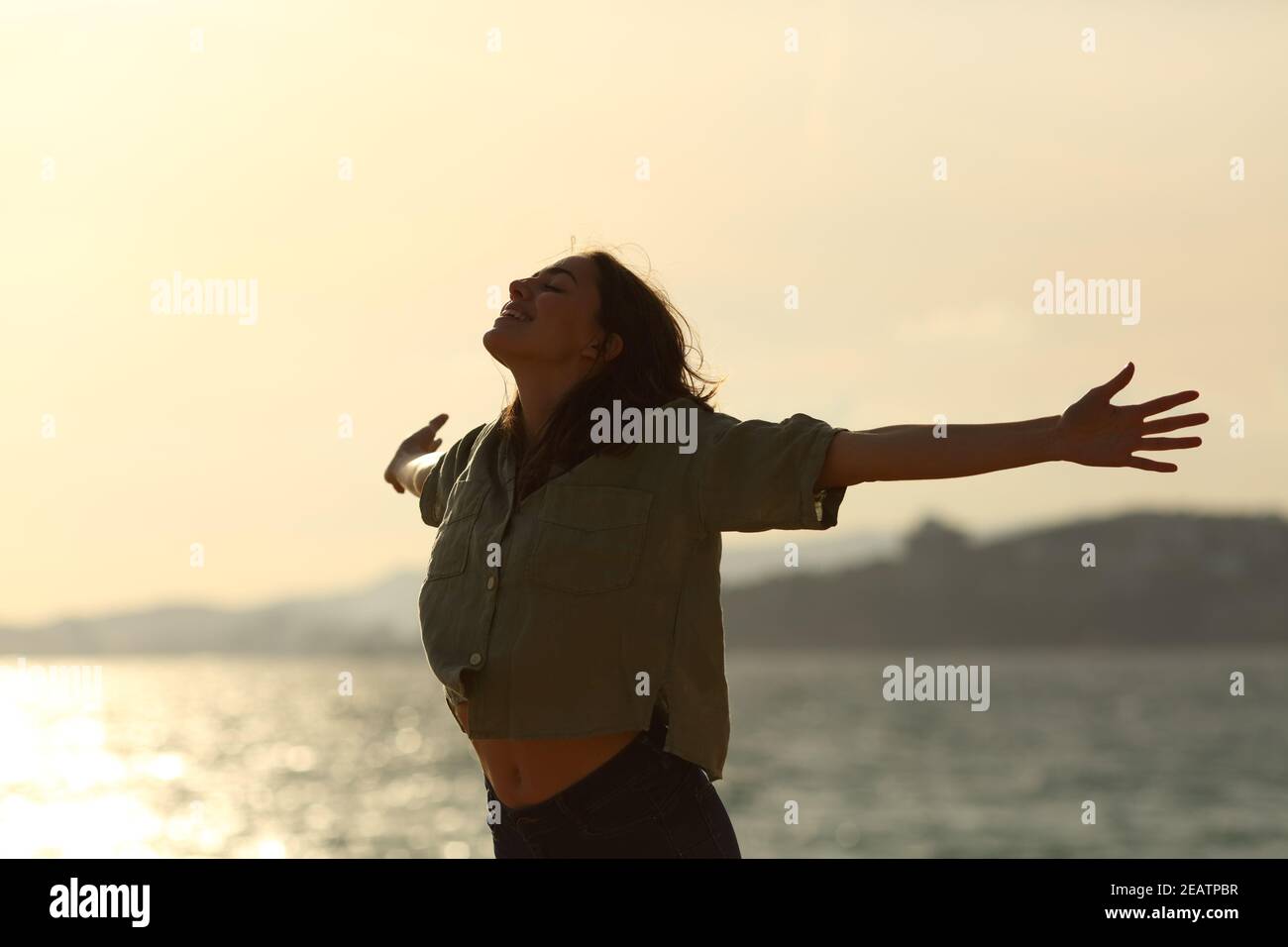 Silhouette de femme excitée qui s'étire les bras sur la plage Banque D'Images