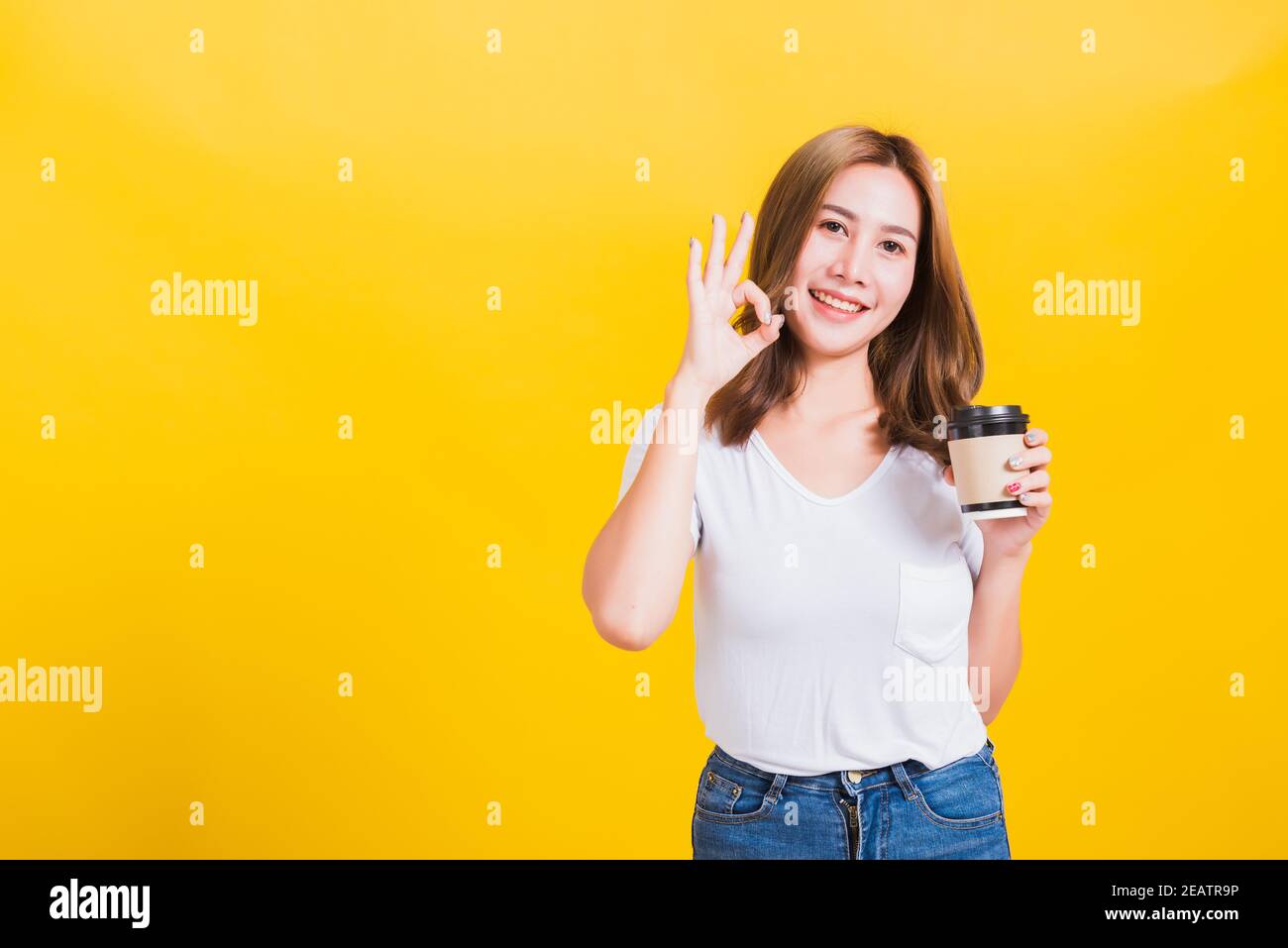 une femme debout tient le papier à café à emporter et confiante Afficher le signe OK Banque D'Images