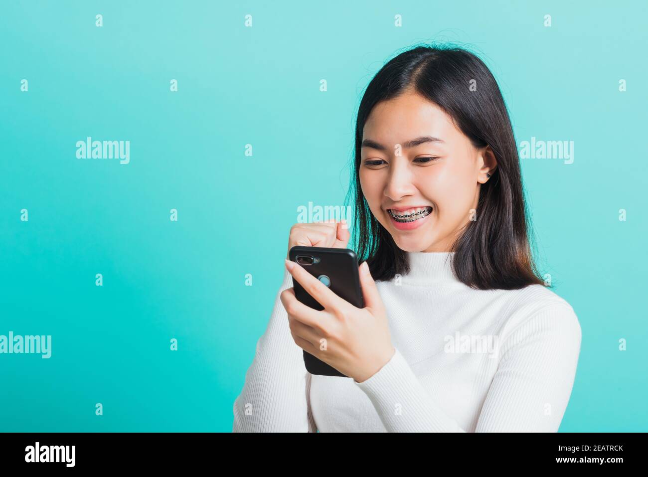 une femme sourit en tenant son smartphone, elle est heureuse et surprise après avoir été reçue message Banque D'Images