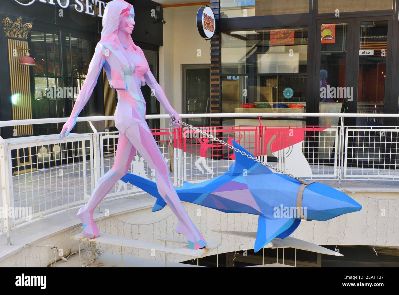 Sculpture colorée au centre commercial - jeune femme marchant un requin- Banque D'Images
