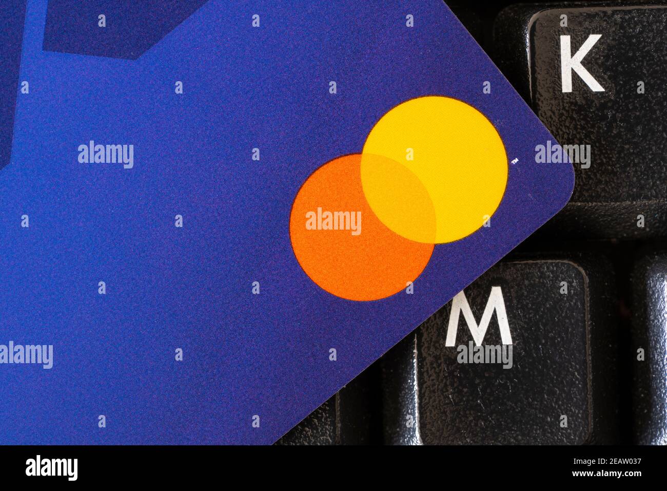 Un gros plan du coin d'une carte de crédit minimaliste sans numéro de carte et le logo Mastercard, reposant sur un clavier. Thème - dette, société sans espèces Banque D'Images