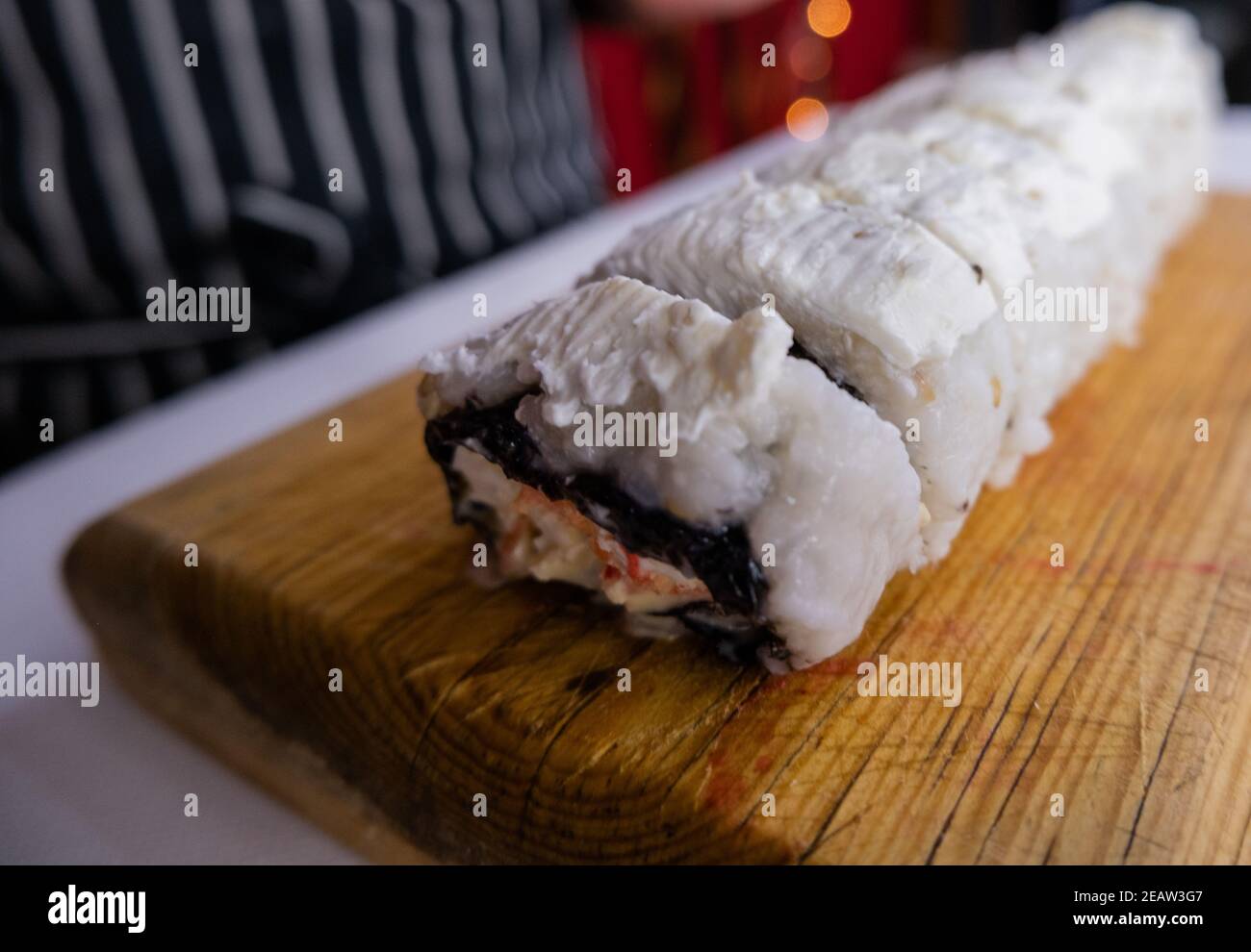 Rouleaux de sushis recouverts de crème blanche sur la planche à découper Banque D'Images