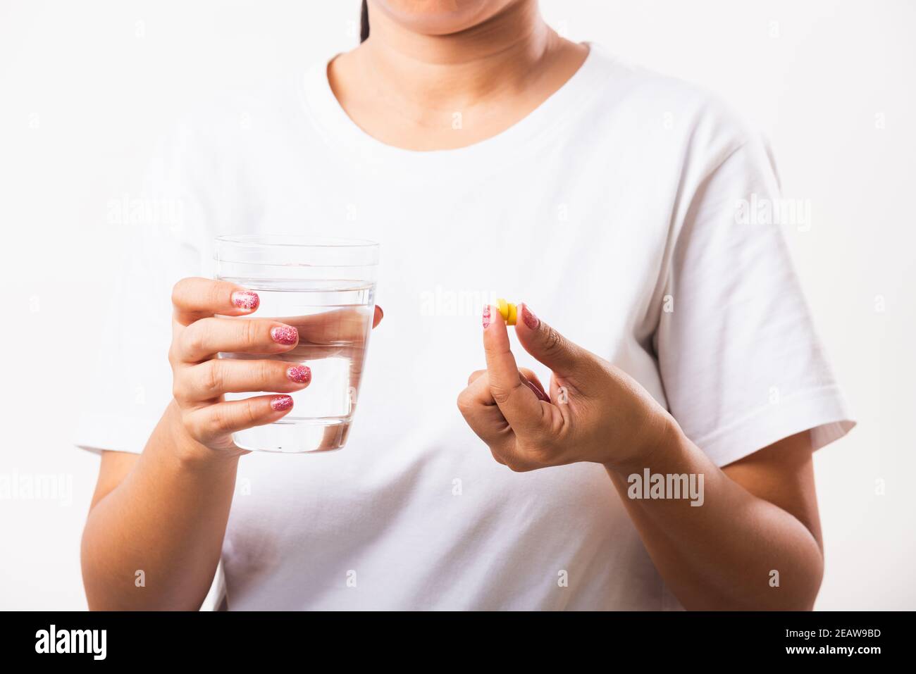 Femme tenir les médicaments de vitamine d'huile de poisson dans la main prêt à prendre médicaments avec un verre d'eau Banque D'Images