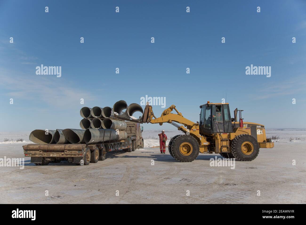 Tuyaux de ponceau de chargement de chargeuses sur pneus pour la construction de la route Inuvik-Tuktoyaktuk, Territoires du Nord-Ouest, Arctique canadien. Banque D'Images