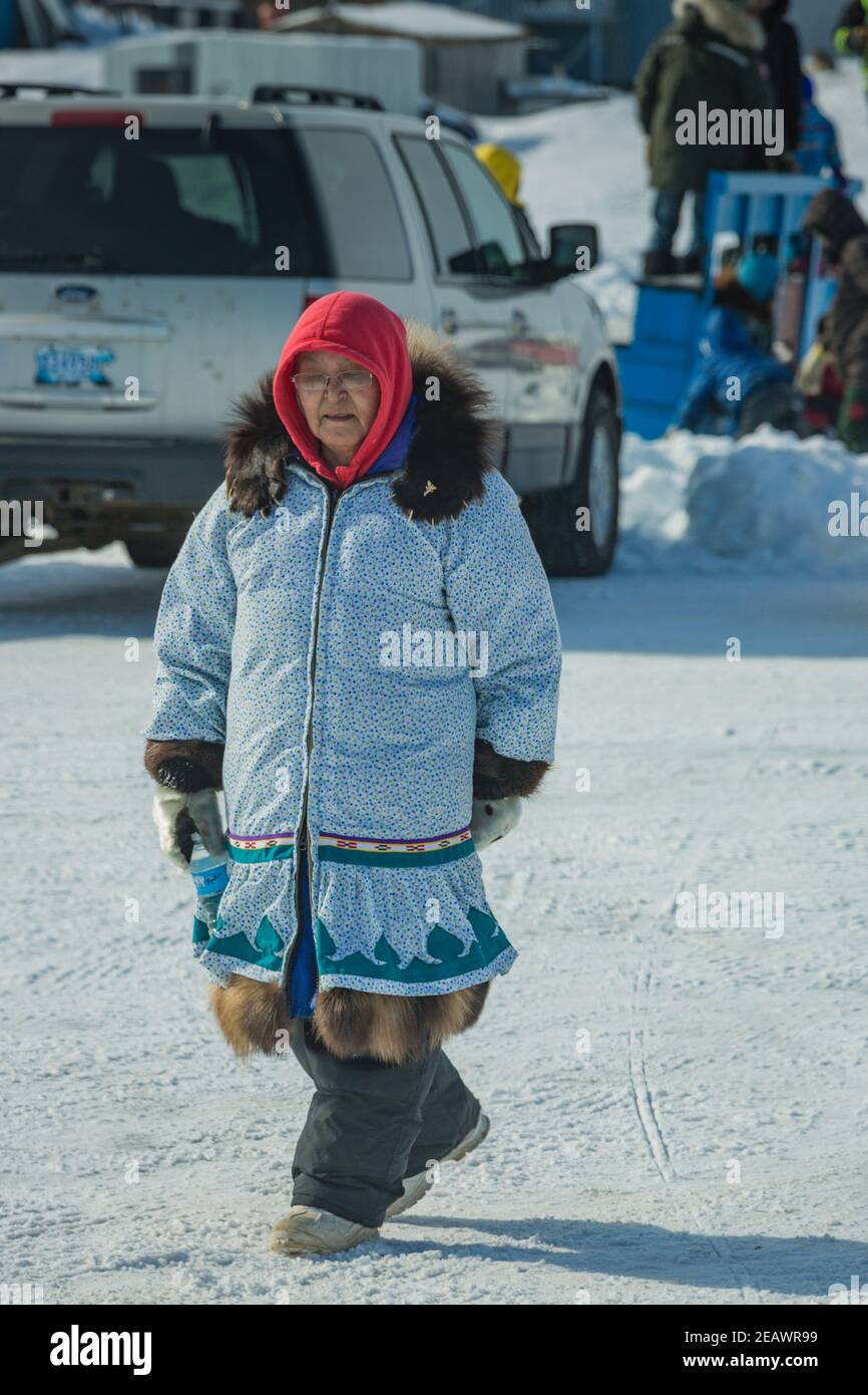Femme autochtone vêtue de parka traditionnelle marchant au béluga Jamboree en hiver, Tuktoyaktuk, Territoires du Nord-Ouest, l'ouest de l'Arctique canadien. Banque D'Images