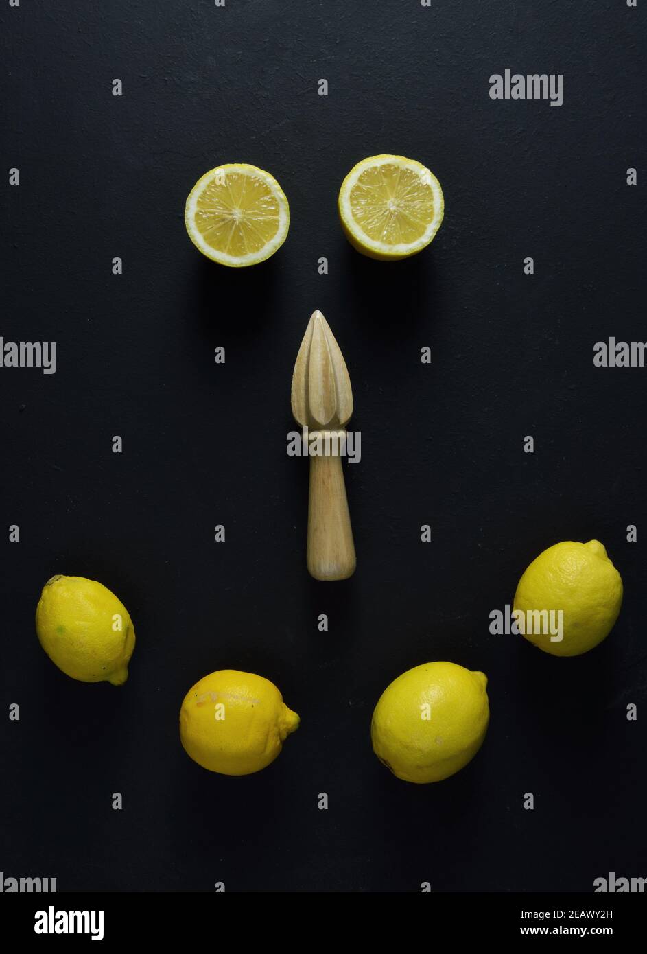 Citrons entiers, demi-citrons et presse-fruits en bois sur fond noir Banque D'Images