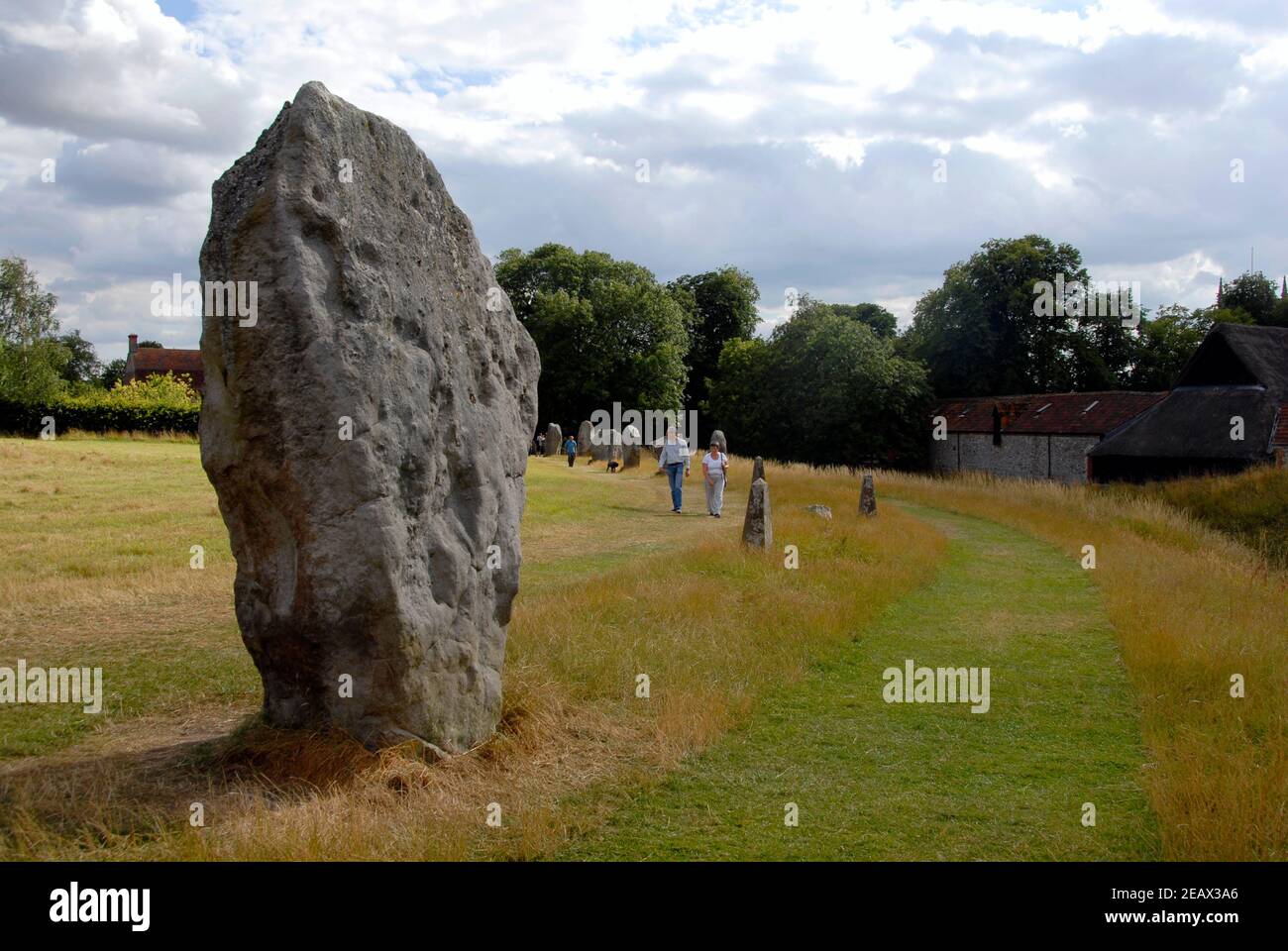 Grande pierre à côté du sentier faisant partie du cercle de pierres, Avebury, Wiltshire, Angleterre avec des visiteurs qui marchent Banque D'Images