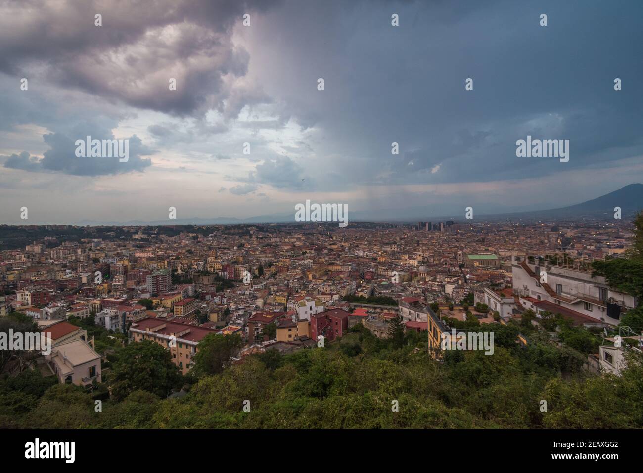 Vue panoramique sur les bâtiments et la verdure de la ville de Naples, dans le sud de l'Italie, pendant un coucher de soleil nuageux. Banque D'Images