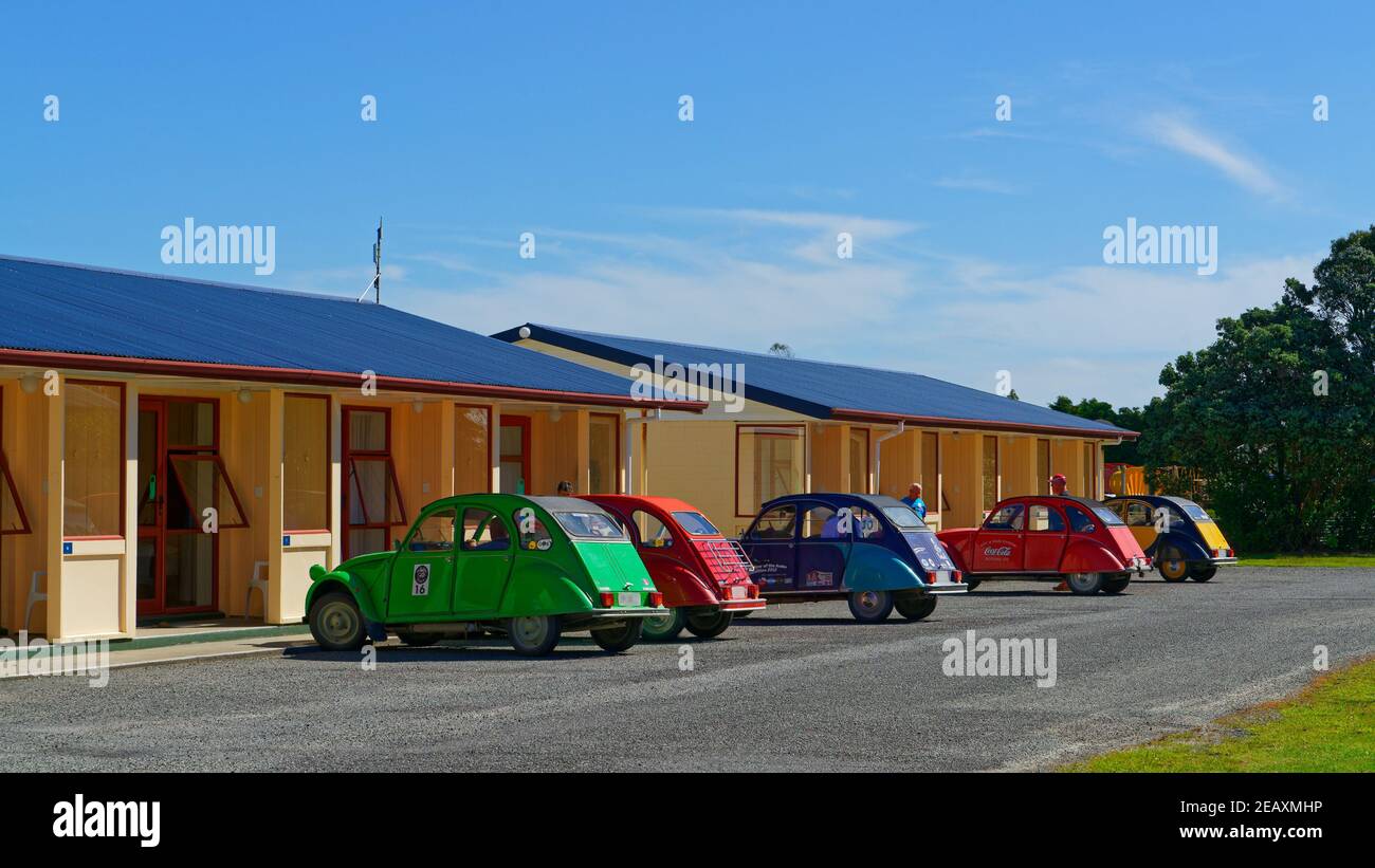 Un groupe de voitures classiques Citroën 2CV dans différentes couleurs, garées à l'extérieur d'un motel, Westport, Nouvelle-Zélande. Banque D'Images