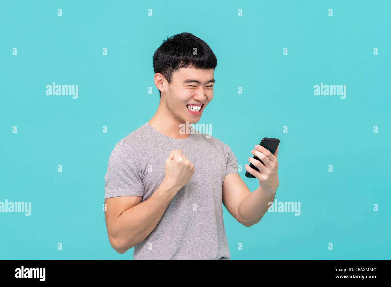 Cool jeune homme asiatique ayant le plaisir de discuter avec son ami appel via vedio isolé sur fond de studio bleu clair Banque D'Images