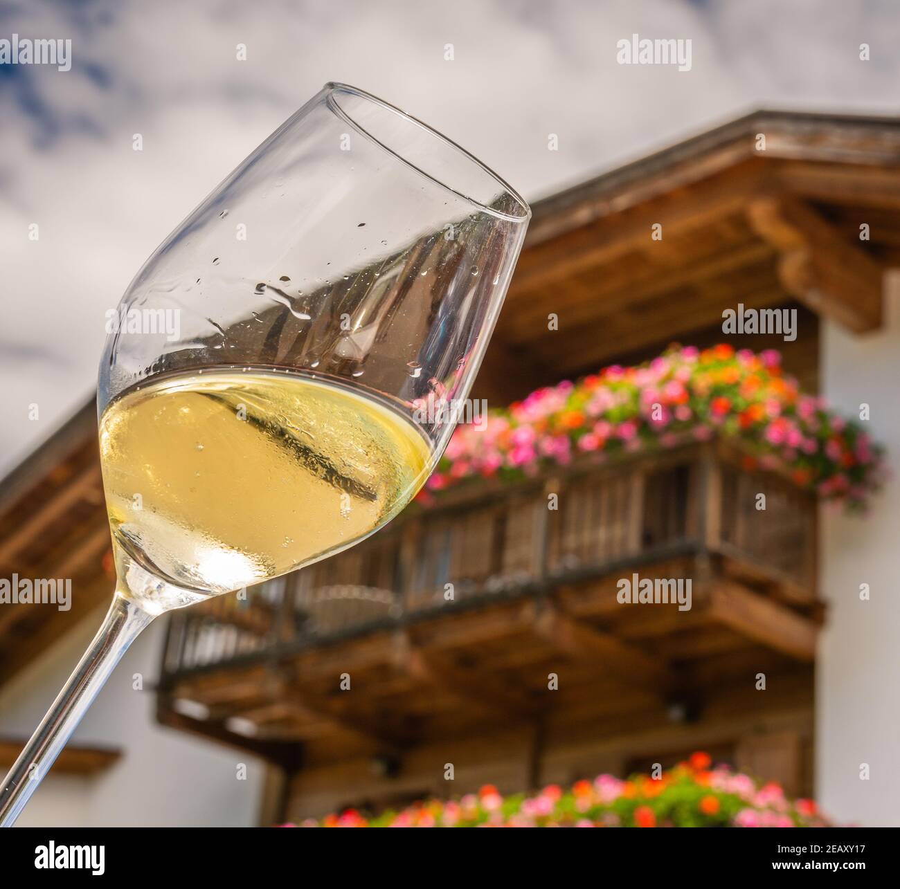 Verre de vin blanc sur un fond typique de maison du Tyrol du Sud. Randonnée dans les Dolomites, Tyrol du Sud, nord de l'Italie Banque D'Images