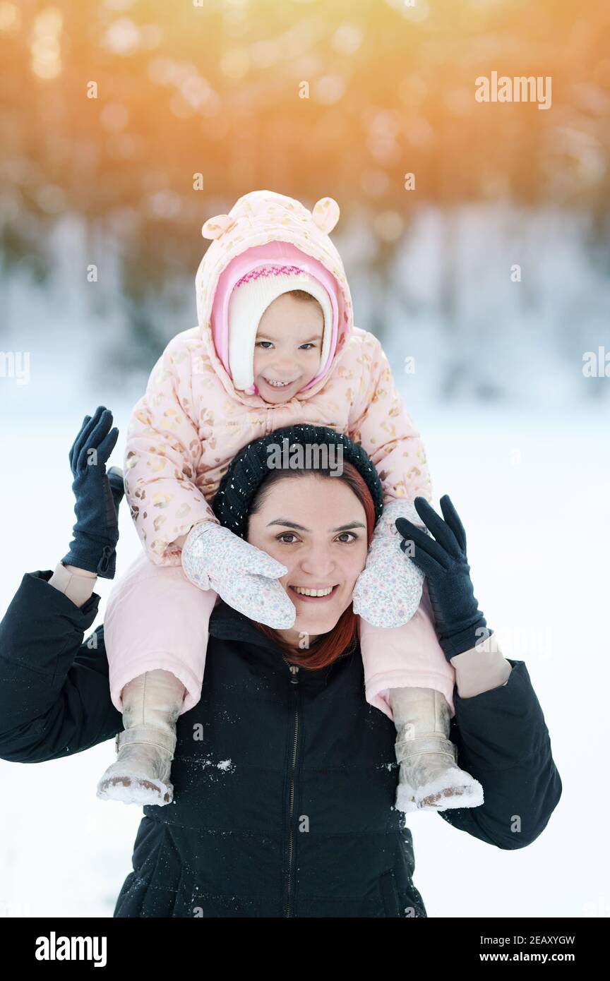 Maman souriante avec un portrait d'enfant sur fond ensoleillé d'hiver Banque D'Images