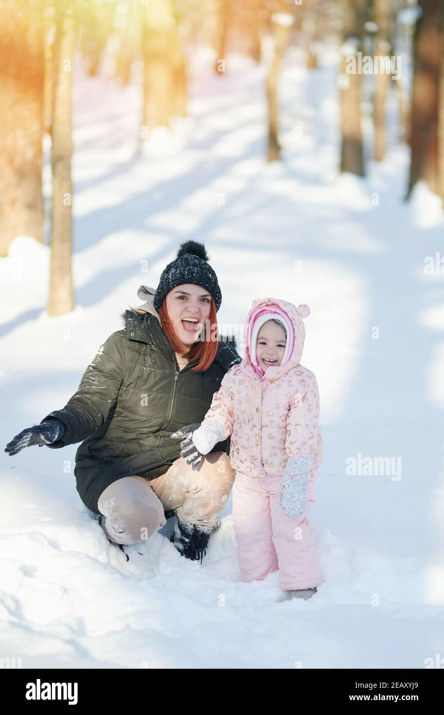 Bonne jeune mère souriante avec sa fille sur le parc de neige en hiver arrière-plan Banque D'Images