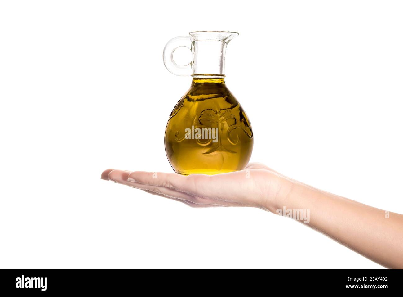 Huile d'olive extra vierge. Huile d'olive extra vierge dans un pot d'huile de verre sur la main d'une femme isolée sur un fond blanc. Banque D'Images