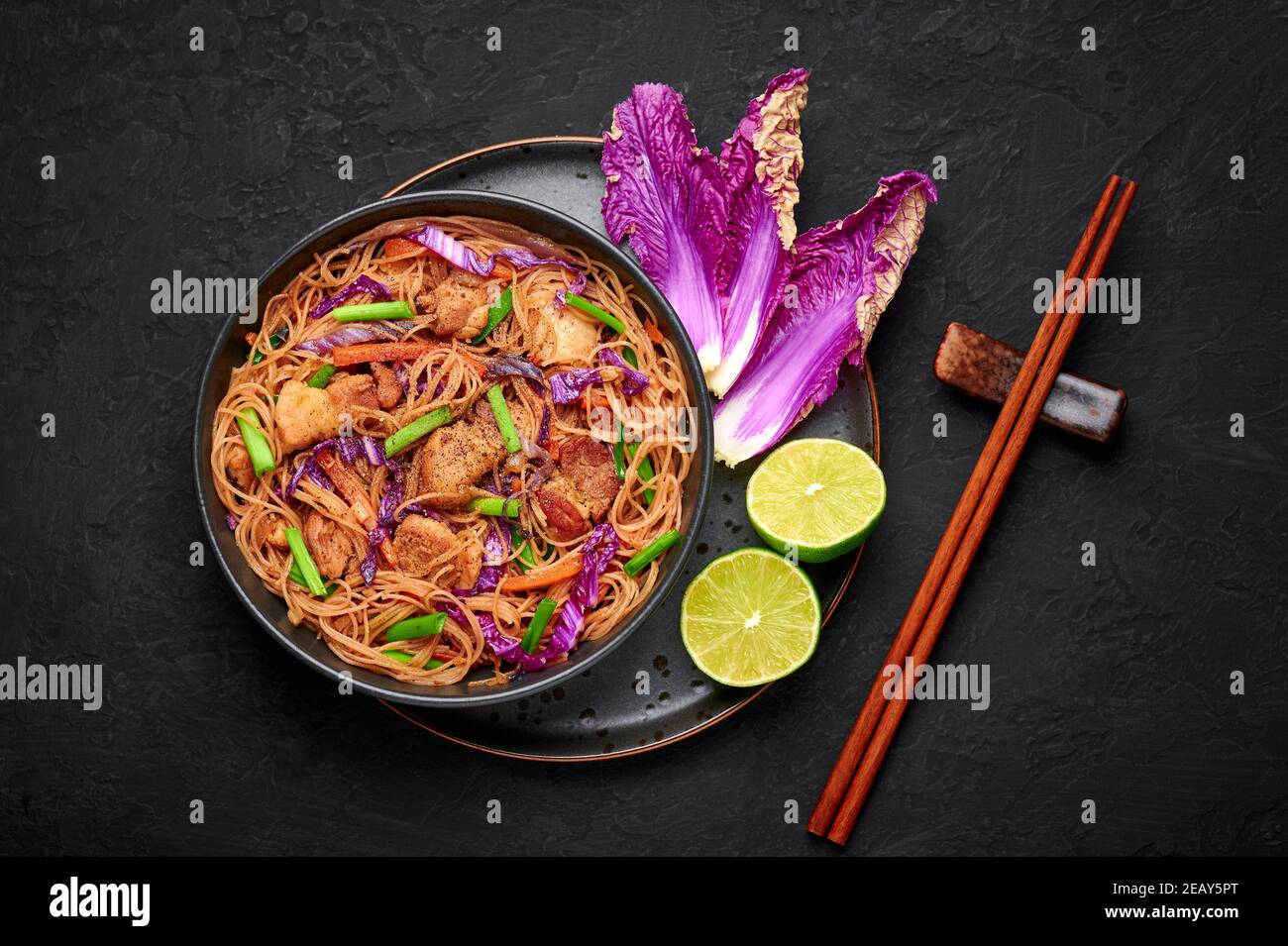 Pancelle Bihon dans un bol noir sur une table en ardoise sombre. Cuisine philippine plat de nouilles avec poitrine de porc, poulet, légumes. Cuisine asiatique. Vue de dessus Banque D'Images