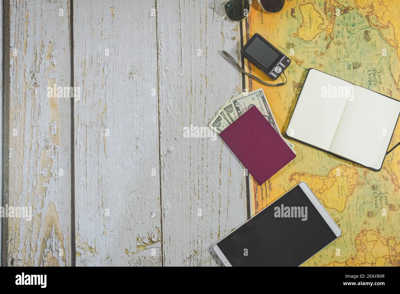 vue du dessus accessoires de voyage. lunettes de soleil, passeport et devises étrangères, appareil photo, ordinateur portable pour prendre des notes, tablette et carte du monde. espace de copie. voyage Banque D'Images