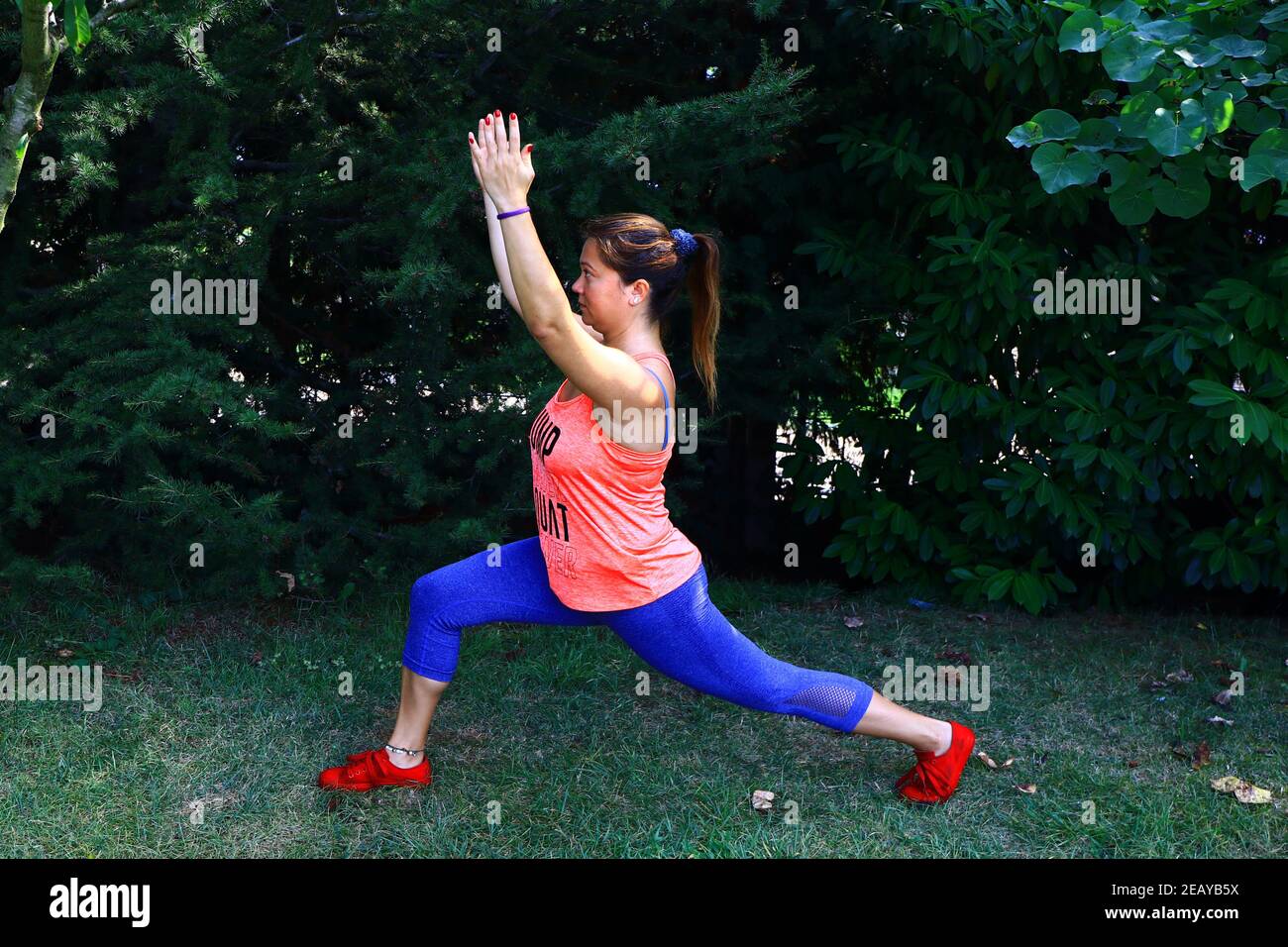 Un instructeur de yoga montre une posture de fente basse sur des herbes vertes. Banque D'Images