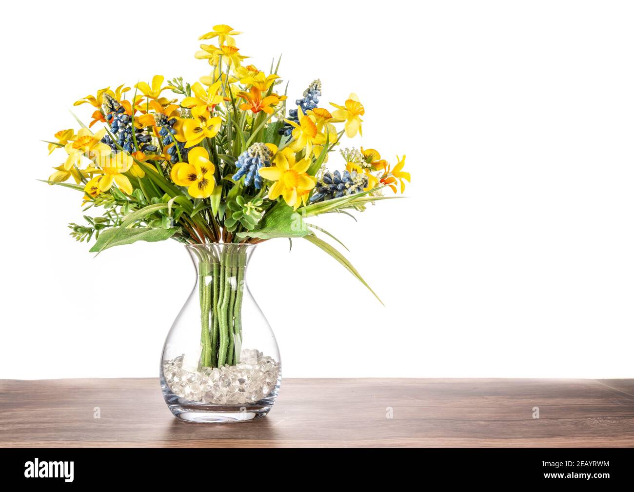 Fleurs artificielles dans un vase en verre avec un fond blanc Uni. Banque D'Images