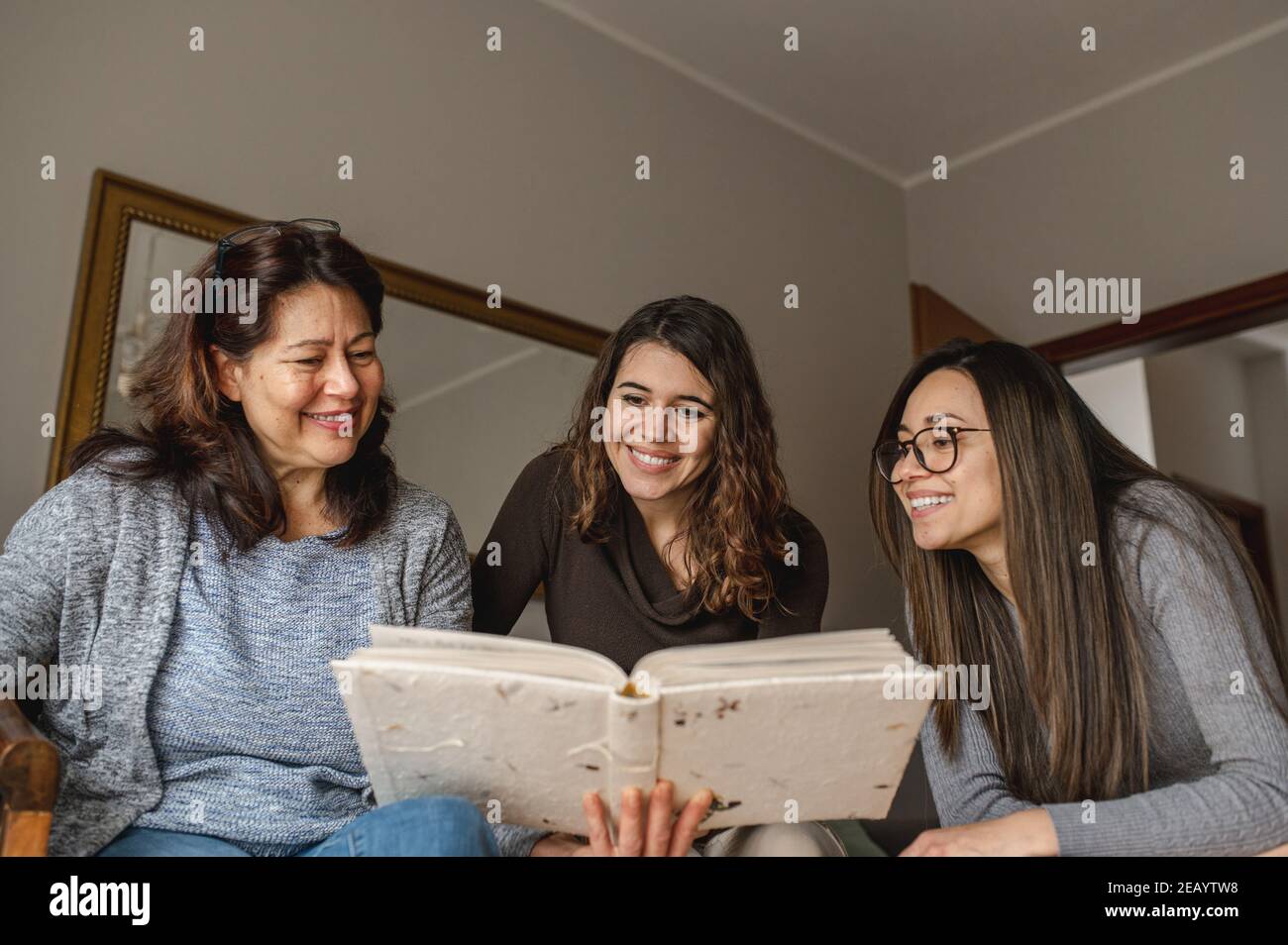 Vue de dessus trois femmes, mère et filles à la recherche d'un livre de souvenirs. Ensemble, concept de famille. Banque D'Images