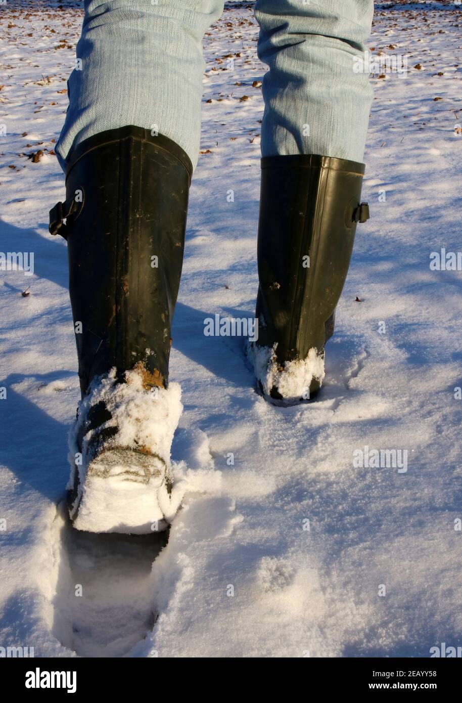 jeune homme marchant dans la neige à bottes wellington Banque D'Images