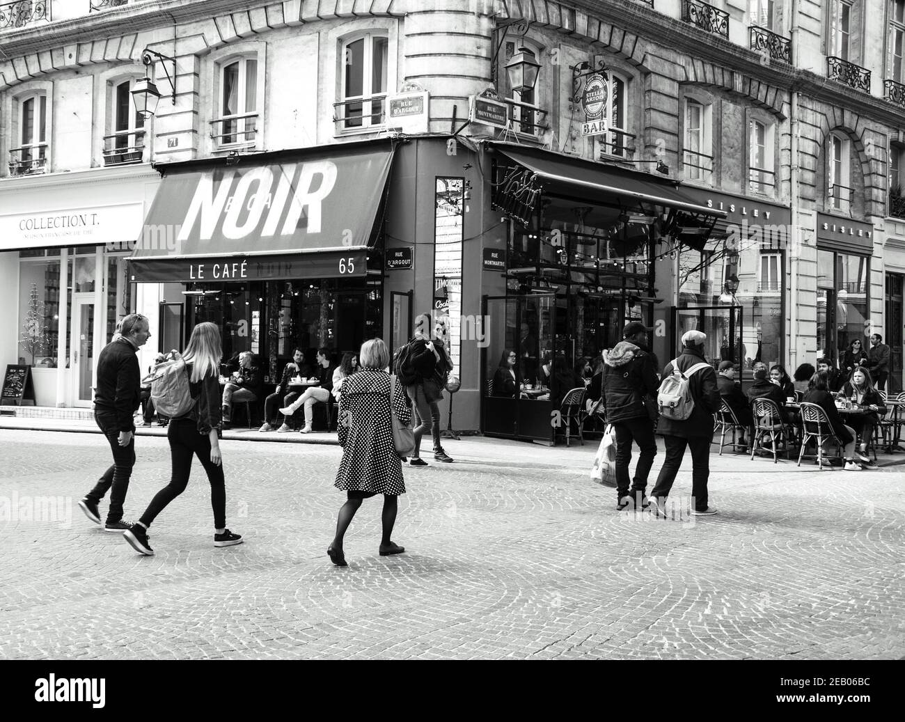 PARIS, FRANCE - 6 AVRIL 2019 : scène urbaine parisienne. Personnes marchant et assis sur la terrasse du café Noir. Photo historique noir blanc Banque D'Images