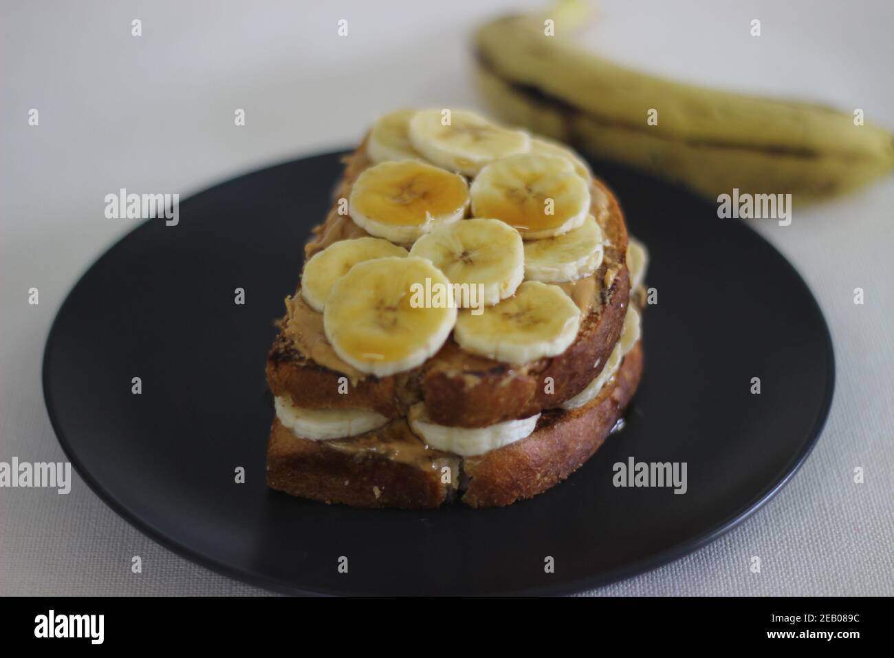Beurre d'arachide banane miel toast sandwich, une idée de petit déjeuner facile. Prise de vue sur fond blanc. Banque D'Images