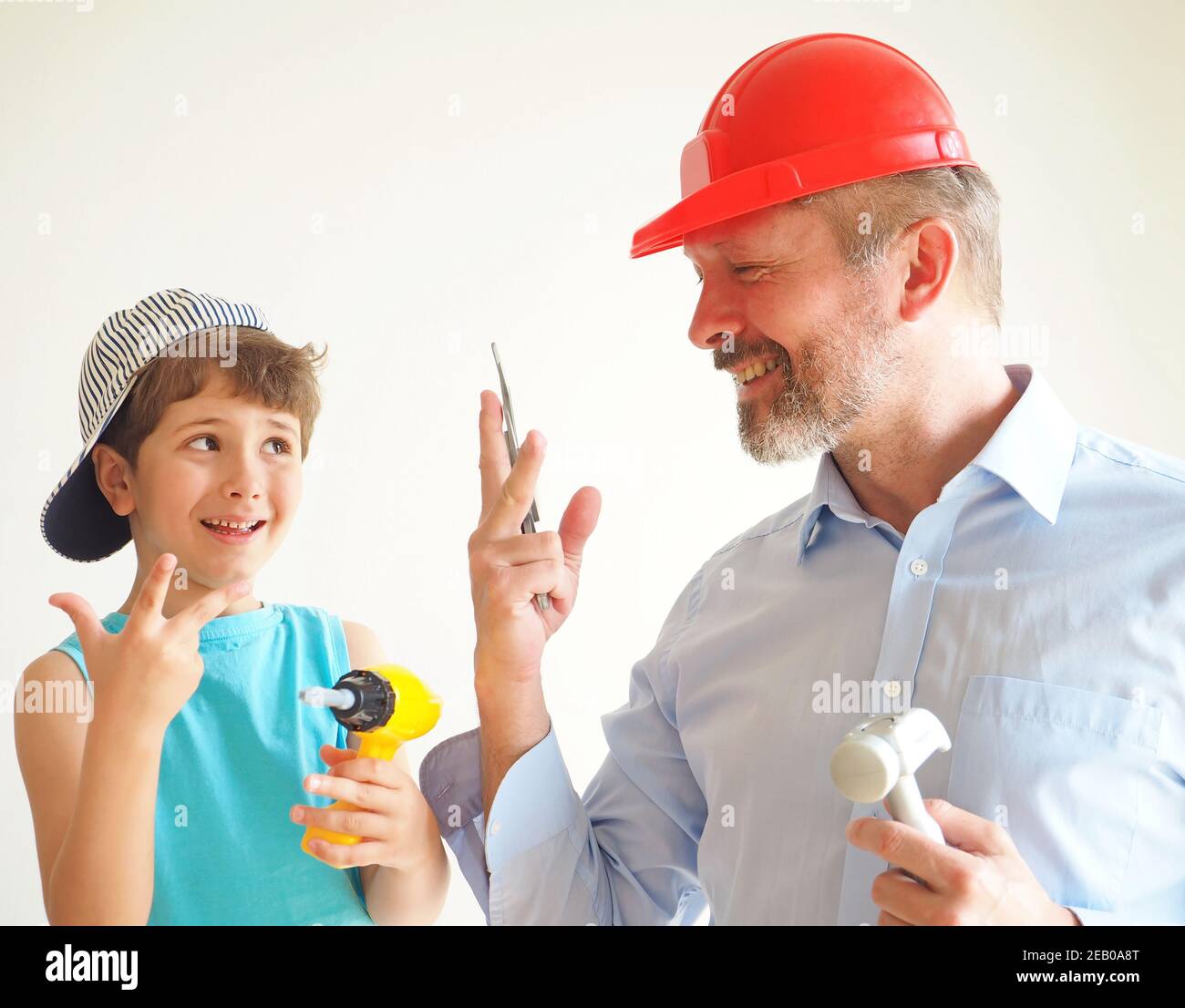 Père et fils jouent des outils en plastique et rient. Ils s'imaginent être des bâtisseurs Banque D'Images