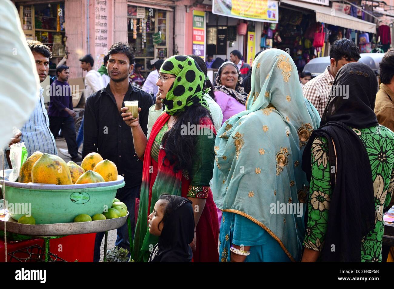 Jaipur, Rajasthan, Inde - novembre, 2016: Une femme indienne dans le hijab a entouré d'autres personnes (hommes et femmes) boit du jus de fruits sur le marché. Banque D'Images