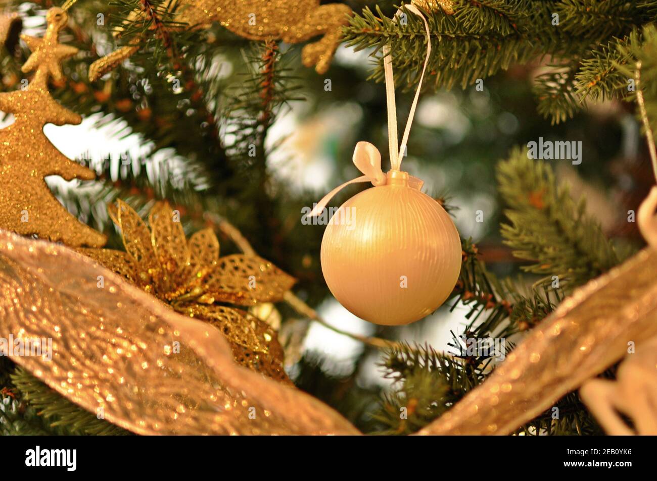 Décoration de Noël accrochée sur une branche dans l'arbre vert, sous forme de boule avec bokeh doux. Gros plan, vue de face Banque D'Images