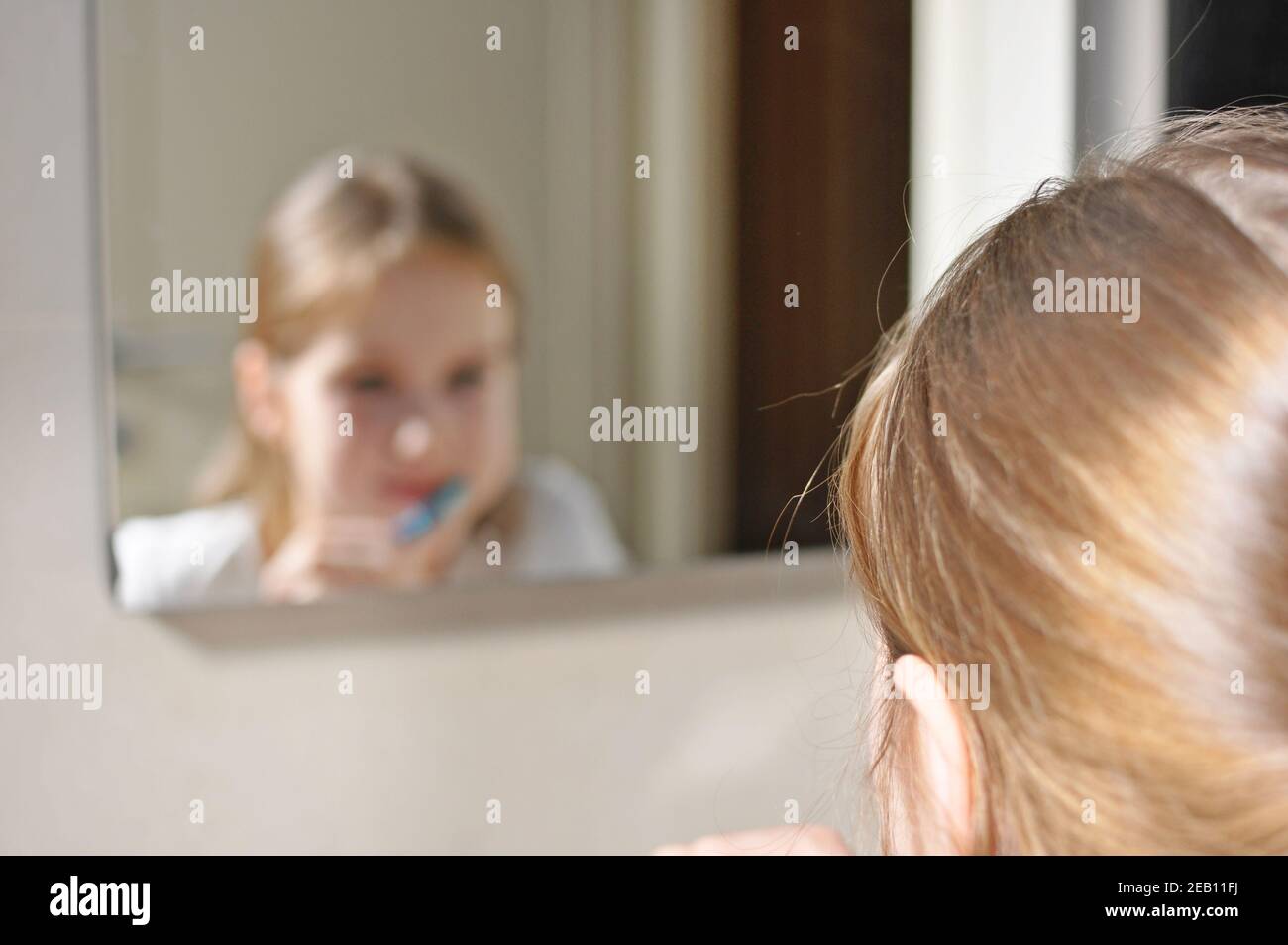 Enfant européen blanc (enfant), fille se lavant les dents avec une brosse à dents dans la salle de bains. Vue symétrique. Concept de soins dentaires. Banque D'Images