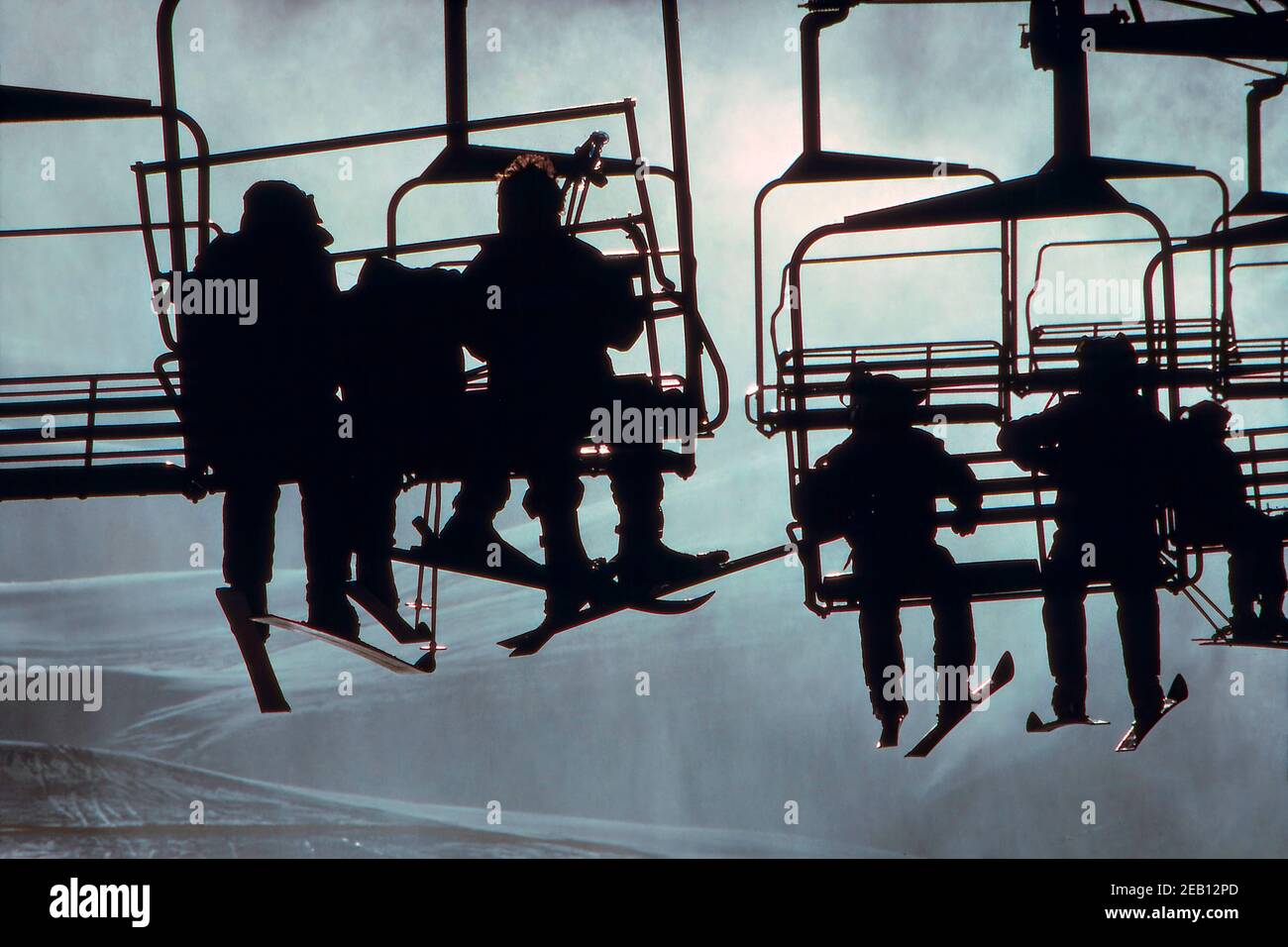 Des enfants silhouetés sont assis sur un télésiège dans une station de ski Banque D'Images