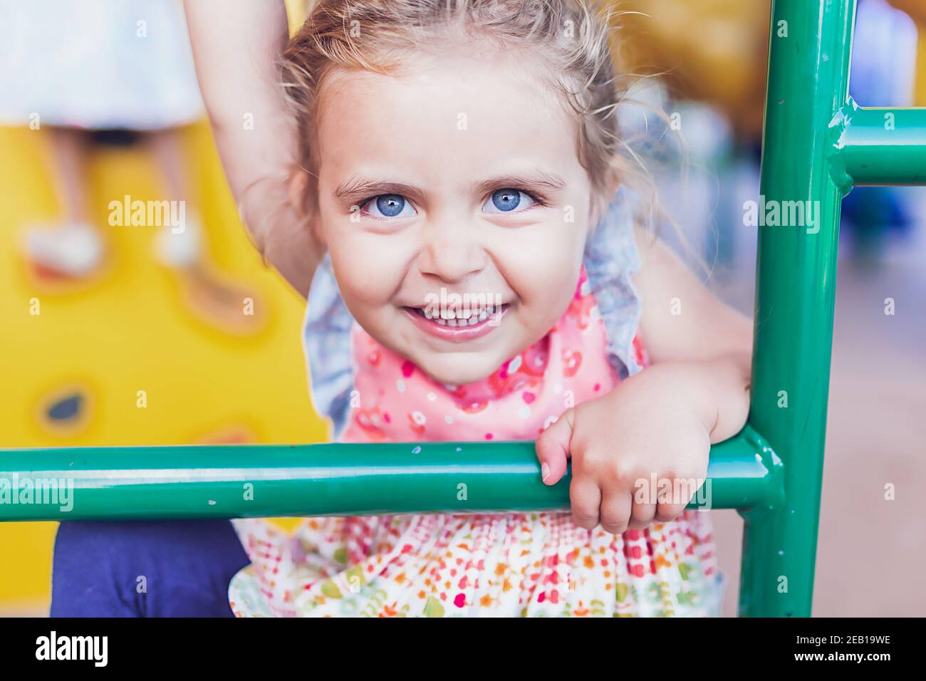 Jeune fille avec de grands yeux bleus jouant sur une aire de jeux publique. Banque D'Images
