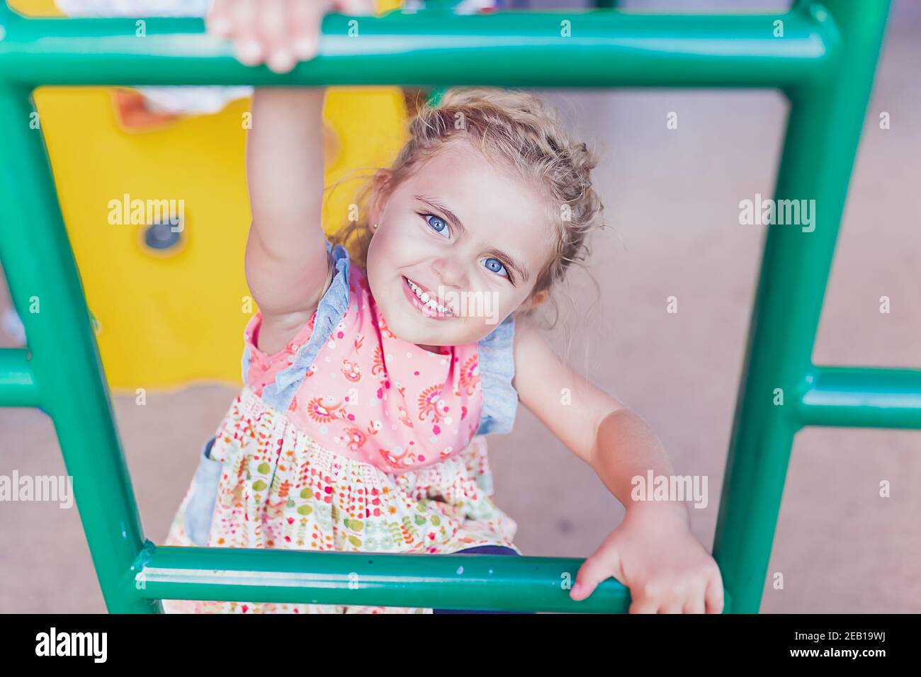 Jeune fille avec de grands yeux bleus jouant sur une aire de jeux publique. Banque D'Images