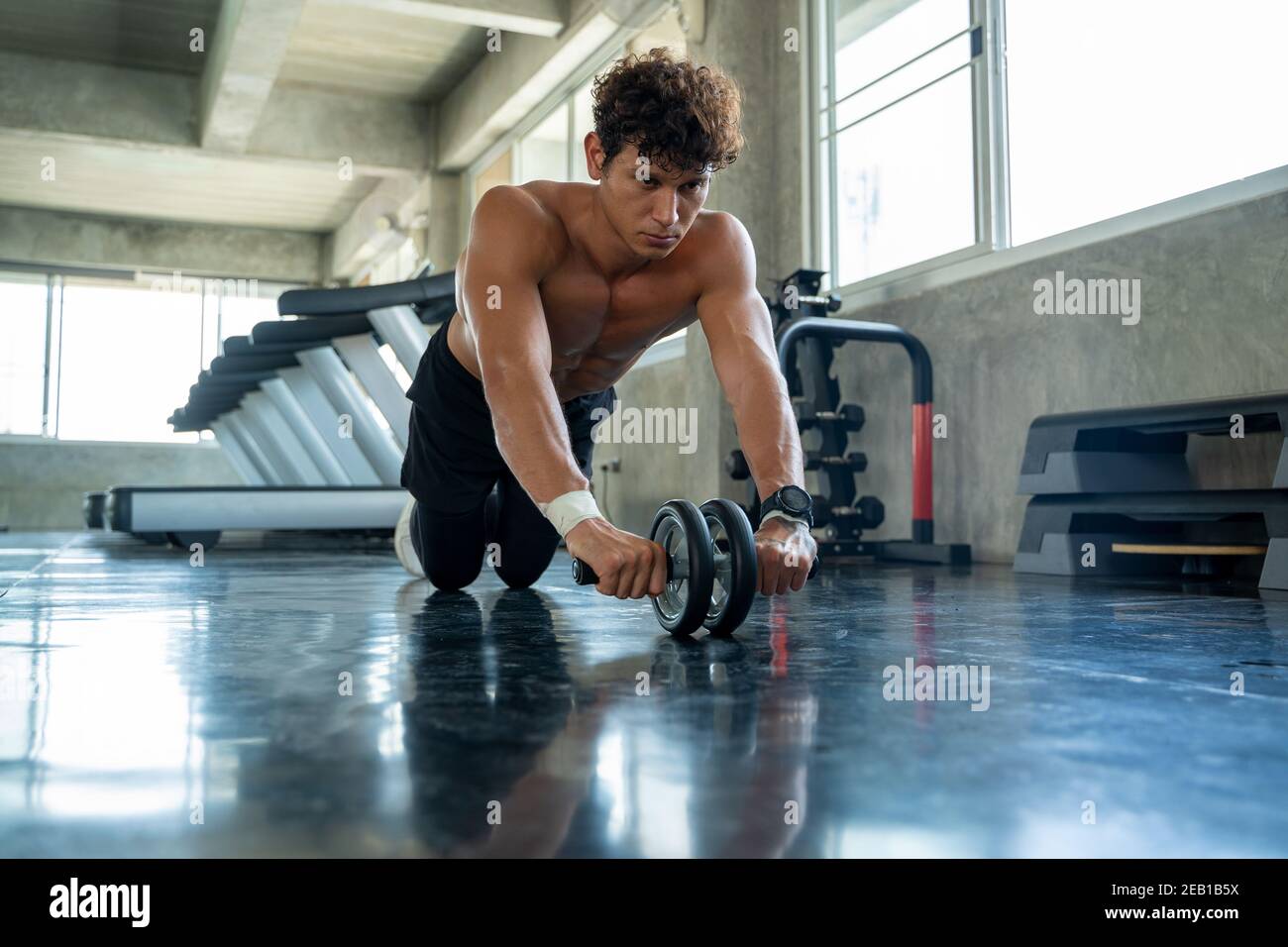 L'homme d'athlétisme s'exerçant avec le rouleau de fitness dans le club de  gym, le concept de muscle de constructeur d'athlète Photo Stock - Alamy