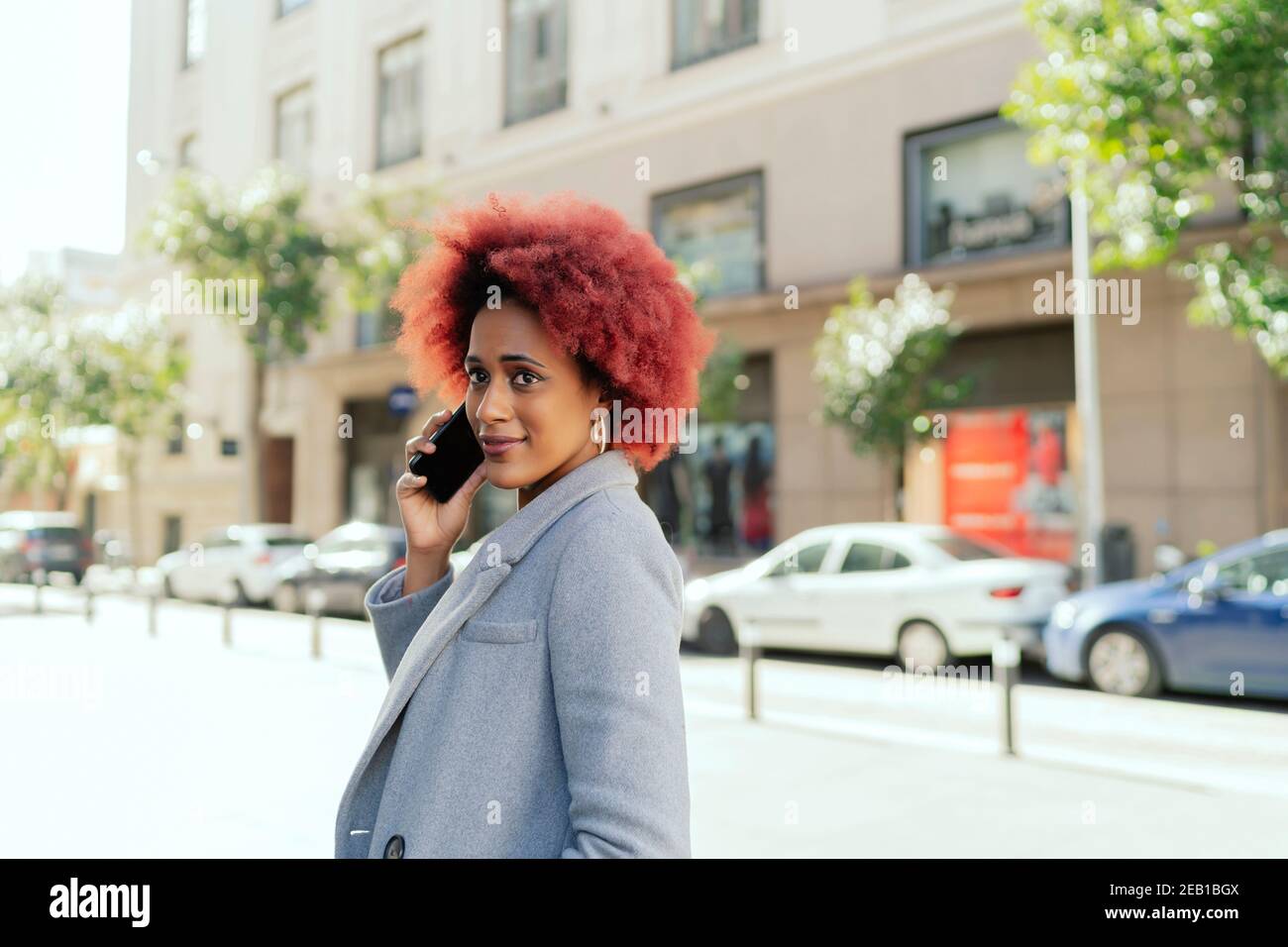 belle femme aux cheveux afro parlant depuis son smartphone Banque D'Images