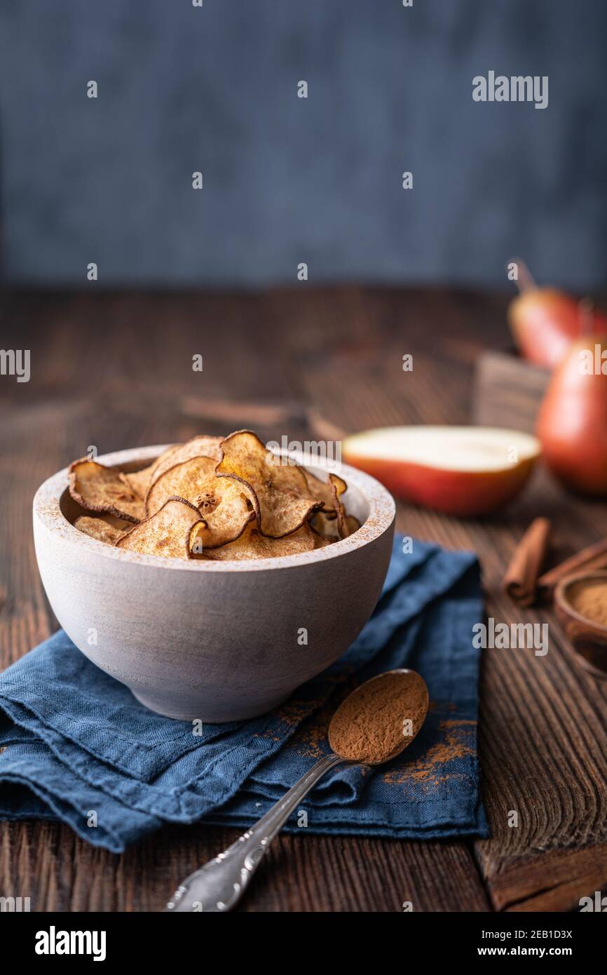 En-cas délicieux et sucré, croustilles de poire croustillantes séchées au four saupoudrées de cannelle sur fond rustique en bois Banque D'Images