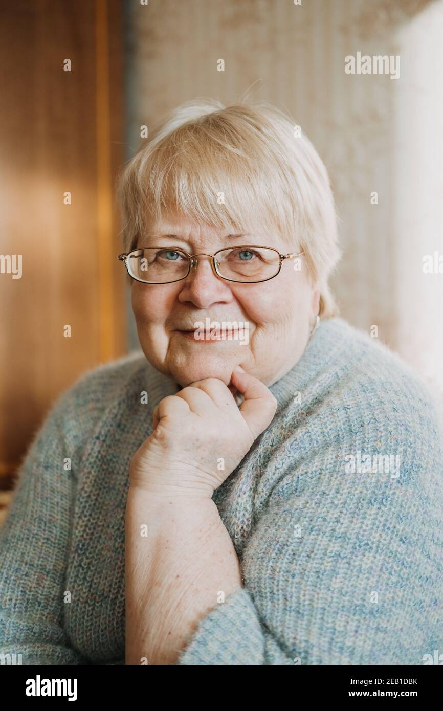 Gros plan portrait authentique et franc de femme blonde senior de grande taille à la maison. Portrait d'une femme mûre à lunettes Banque D'Images