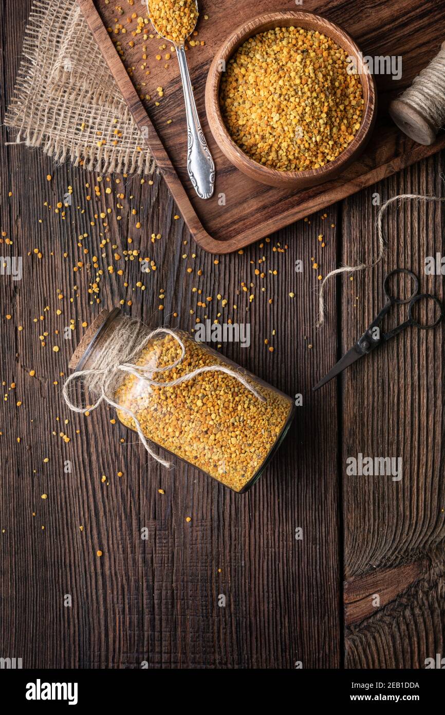 Complément alimentaire sain, pollen d'abeille super-alimentaire dans une bouteille en verre et un bol avec espace de copie sur fond rustique en bois Banque D'Images