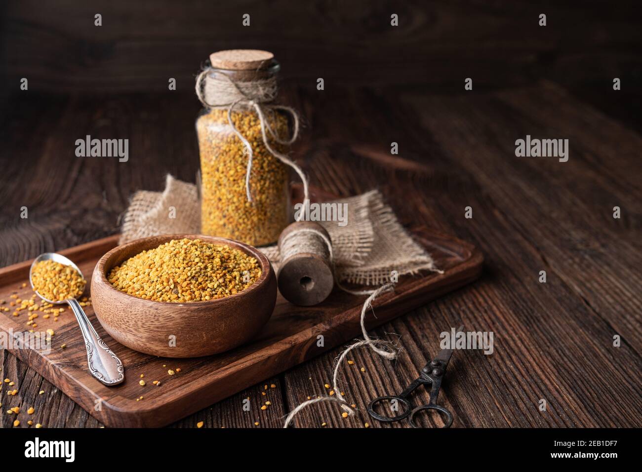 Complément alimentaire sain, pollen d'abeille super-alimentaire dans une bouteille en verre et un bol avec espace de copie sur fond rustique en bois Banque D'Images