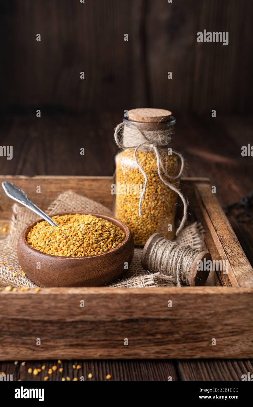 Complément alimentaire sain, pollen d'abeille super-alimentaire dans une bouteille en verre et un bol avec espace de copie sur fond rustique en bois Banque D'Images