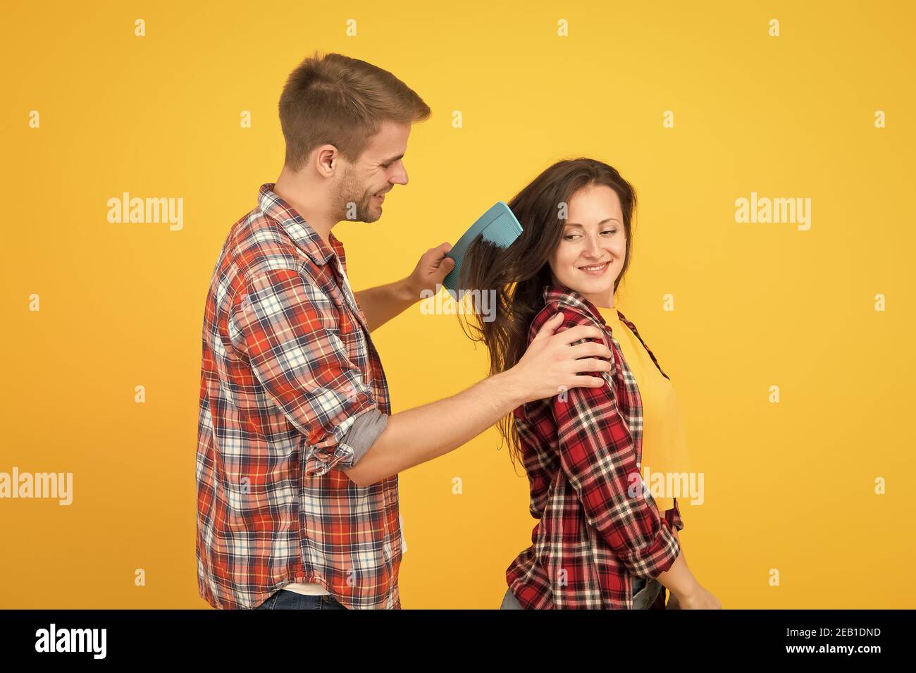 Soins capillaires à la maison. Pour une coiffure plus aiderez. Couple s'amusant avec le grand sabot. Peignez et brossez vos cheveux. Homme et femme prenant soin des cheveux eux-mêmes. Services de coiffeur. Ambiance créative. Changer de cheveux. Banque D'Images